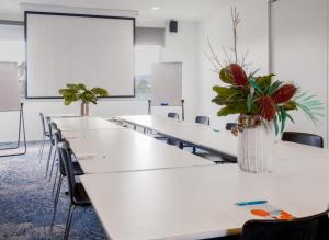 a classroom with tables and chairs with a vase of flowers at Mantra Hobart Airport in Hobart