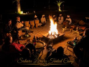 a group of people sitting around a fire at Sahara Luxury Tented Camp in Merzouga