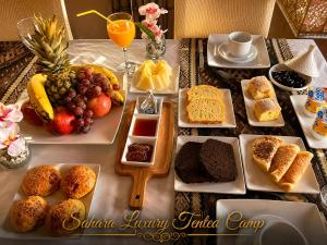 a table topped with different types of bread and fruit at Sahara Luxury Tented Camp in Merzouga