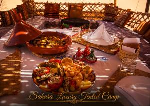 a table with a plate of food on it at Sahara Luxury Tented Camp in Merzouga +25 photos