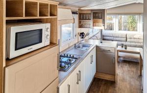 a kitchen with a microwave and a sink at 2 Bedroom Cozy Stacaravan In Makkum in Makkum