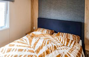 a bed with a blue headboard and two pillows at 2 Bedroom Cozy Stacaravan In Makkum in Makkum +6 photos
