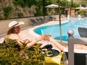two women sitting at a table near a swimming pool at Novotel Roma Est in Rome