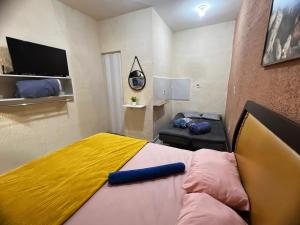 a small bedroom with a bed with a yellow blanket at Recanto Carioca Aconchegante in Rio de Janeiro