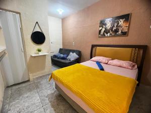 a bedroom with a bed with a yellow blanket on it at Recanto Carioca Aconchegante in Rio de Janeiro