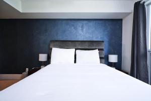 a bedroom with a large white bed with a blue wall at Union Centre Hotel & Suites in Toronto