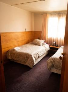 a bedroom with two beds and a window at Hostal y piezas individuales in Coihaique