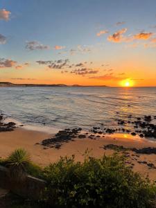 a sunset over the ocean with a bunch of rocks at Pipa Mar Hotel in Pipa
