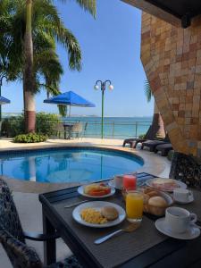 a table with food and drinks next to a swimming pool at Pipa Mar Hotel in Pipa