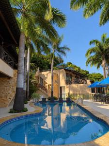 a swimming pool with palm trees in front of a building at Pipa Mar Hotel in Pipa +6 photos