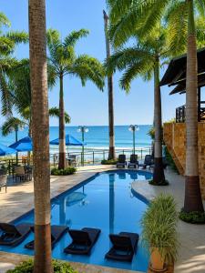 a swimming pool with palm trees and the ocean at Pipa Mar Hotel in Pipa
