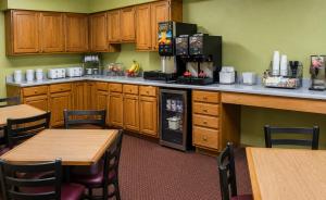 a kitchen with wooden cabinets and wooden tables and chairs at Super 8 by Wyndham Arkansas City KS in Arkansas City
