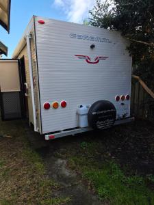 a white trailer is parked in the grass at Luxury Caravan at 10 in Oakleigh +4 photos