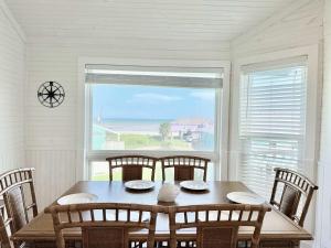 a dining room with a table and chairs and a window at Sandy Beach Retreat and Gulf View in Galveston