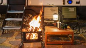 a fire pit in front of a camper with a table at Sokcho Supuro Caravan in Sokcho