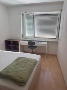 a bedroom with a bed and a desk and a window at Basel Shared Apartment in Basel +1 photo