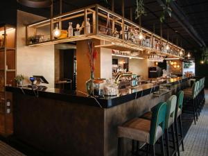 a bar with a long counter with green chairs at Hotel Mercure Roma Corso Trieste in Rome