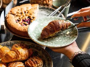 a person holding a plate of croissants and other pastries at Hotel Mercure Roma Corso Trieste in Rome