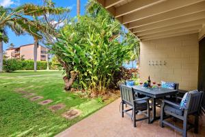 a patio with a table and chairs in a yard at Maui Sands 3C in Honokowai