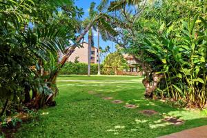 a garden with green grass and trees and a building at Maui Sands 3C in Honokowai