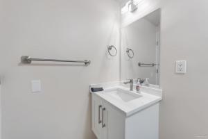 a white bathroom with a sink and a mirror at Bright Maple Suite in Richmond