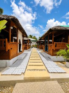 a walkway leading to a resort with wooden buildings at Teteng's Apartelle in San Vicente