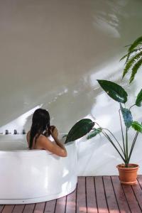 a woman sitting in a bath tub next to a plant at Arenal Pecpen in Fortuna +36 photos