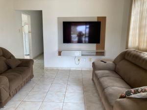 a living room with two couches and a flat screen tv at Casa de temporada Passos MG in Passos