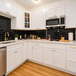 a white kitchen with white cabinets and a microwave at High Falls Studio TV Kitchen Downtown Rochester in Rochester