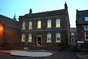 un antiguo edificio de ladrillo con sus luces encendidas en Parade School Guest Rooms, en Berwick-Upon-Tweed