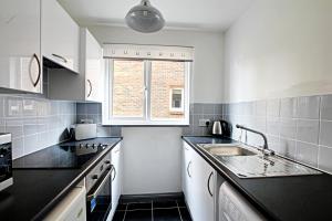 uma cozinha branca com um lavatório e uma janela em The Willows em Crawley