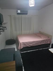 a bedroom with a bed with pink sheets and a rug at Pousada de Isa in Palhoça