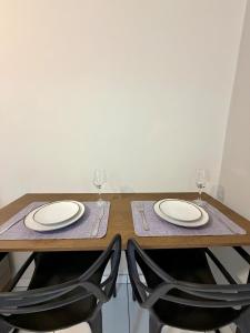 a wooden table with two chairs and two wine glasses at Apto com 2 quartos e A/C no Centro in Montes Claros