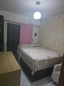 a bedroom with a bed with a pink curtain at Pousada de Isa in Palhoça