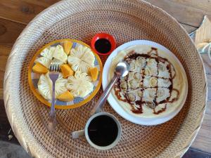 a table with two plates of food and a cup of coffee at AWAN Homestay in Kuta Lombok