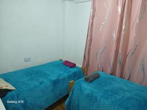 a bedroom with two beds and a curtain at Alojamiento UMA in Puerto Iguazú