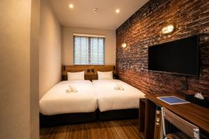 a bedroom with two beds and a brick wall at KAJAhause in Osaka