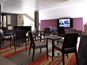 a waiting room with tables and chairs and a flat screen tv at Mercure Hexagone Luxeuil in Luxeuil-les-Bains
