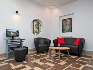 a waiting room with a couch and chairs and a tv at ibis Berlin City Süd in Berlin