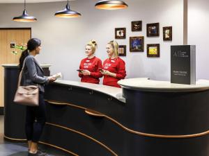 two women standing at the reception counter of a salon at ibis Hotel Northampton Centre in Northampton