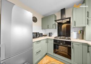 a kitchen with green cabinets and a stove top oven at 2Br House I Sleeps 4 I Cumbernauld in Cumbernauld