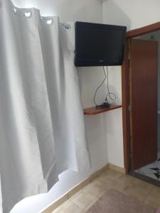 a room with white curtains and a television on a wall at Pousada Maia em Flor chale azul in Resende
