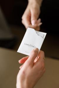 two hands holding a piece of paper with the words grandedia at Grand Duka Hotel & SPA in Durrës