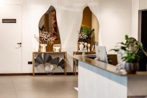 a lobby with a counter with flowers and a mirror at Grand Duka Hotel & SPA in Durrës