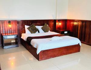 a bedroom with a bed with a wooden headboard at Mongkol Angkor Residence in Phumĭ Trăm Néak