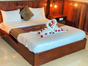 a bed with a swan decoration on it at Mongkol Angkor Residence in Phumĭ Trăm Néak