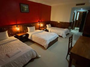 a hotel room with two beds and a red wall at Mongkol Angkor Residence in Phumĭ Trăm Néak
