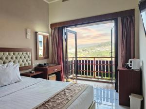 a bedroom with a bed and a balcony with a view at Spencer Green Hotel Batu in Punten