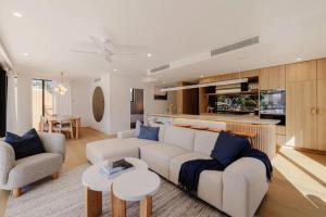 a living room with a couch and chairs and a kitchen at Esprit Holidays Rainbow Bay in Gold Coast