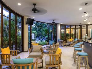 a restaurant with chairs and tables and windows at Ibis Phuket Patong in Patong Beach